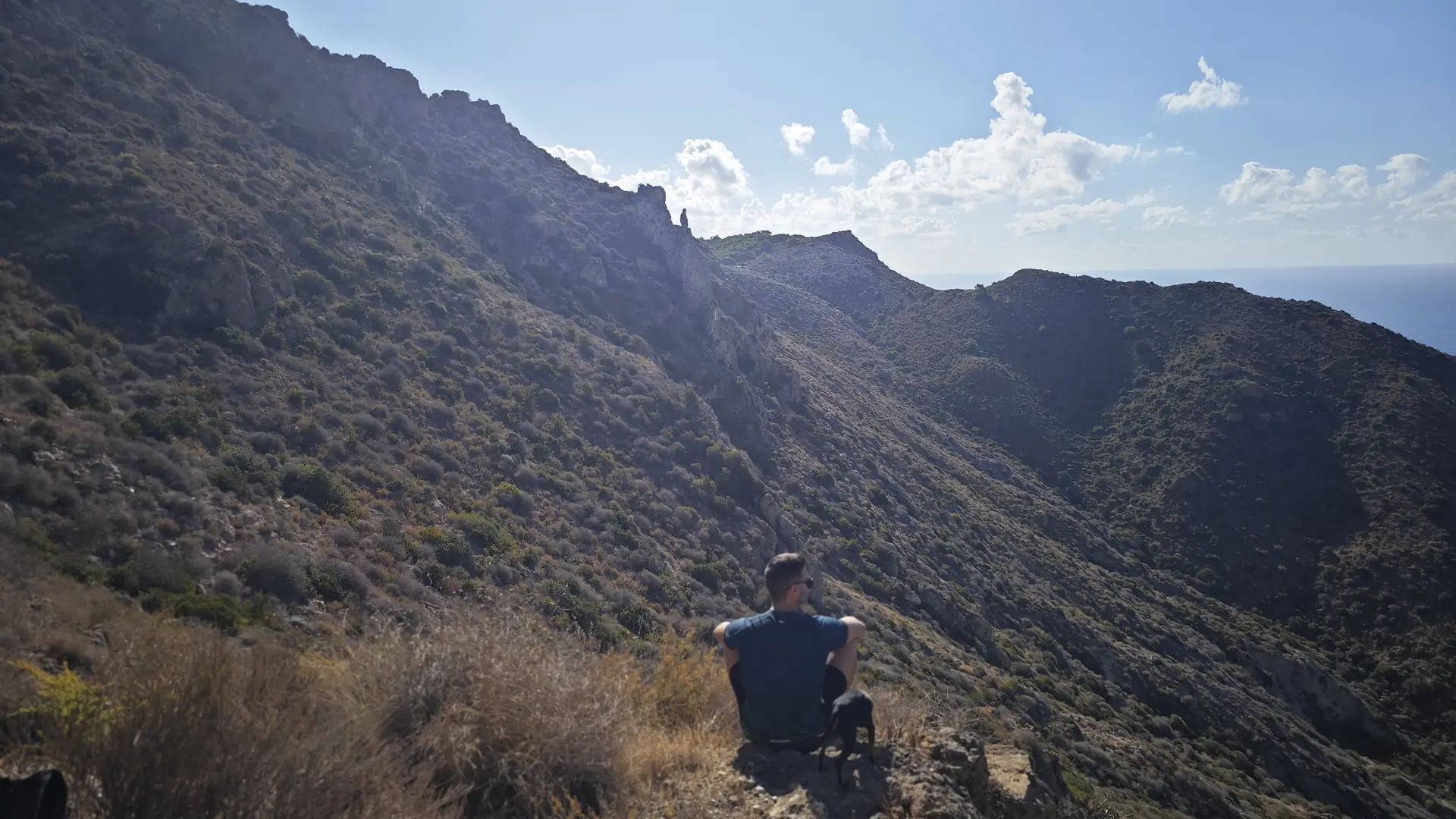 José, sentado de espaldas en la ladera de un monte, con su perro